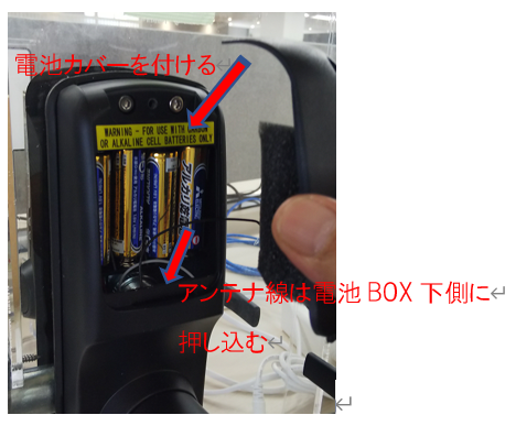 アンテナ線を電池ボックスの下側に押し込み、電池カバーを付けるところ