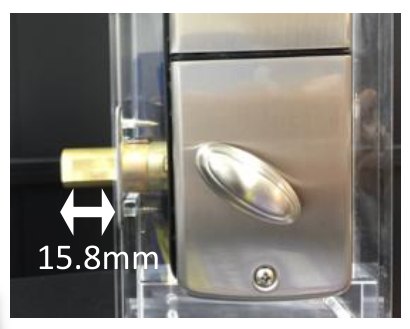 デッドボルトが施錠の位置まで出ている写真。扉の側面から15.8mm飛び出している（シルバーの屋内側の本体を透明の見本の扉に取り付けたもの）