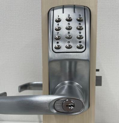 RemoteLOCK 700i（シルバー）を扉に取り付けた写真。屋外側のテンキーとレバーハンドル、物理鍵のシリンダー