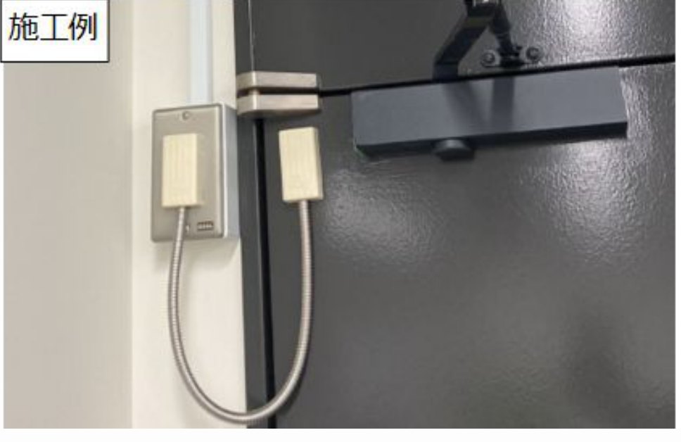 扉の横の壁に付けたスイッチプレートから、フレキシブルチューブで扉側の通電金具へつないだ施工例の写真