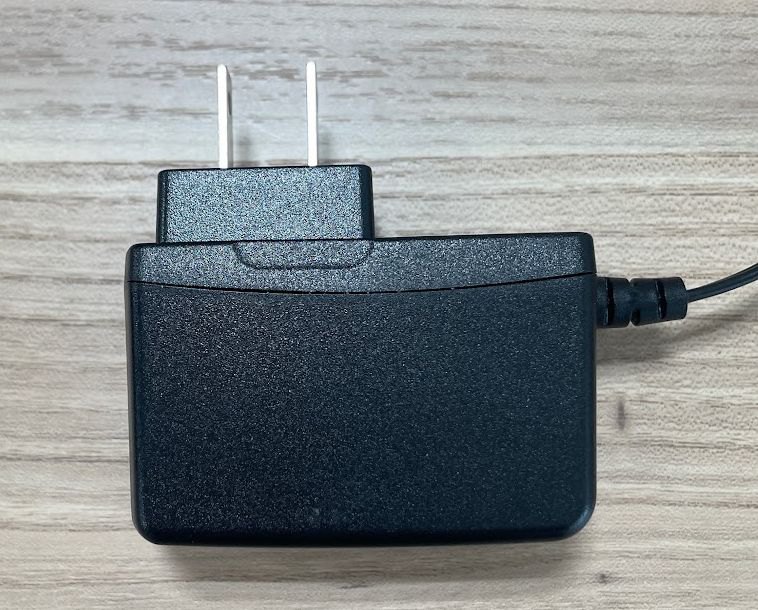 黒い電源アダプターの写真。本体の上面にプラグ、側面からコードが出ている